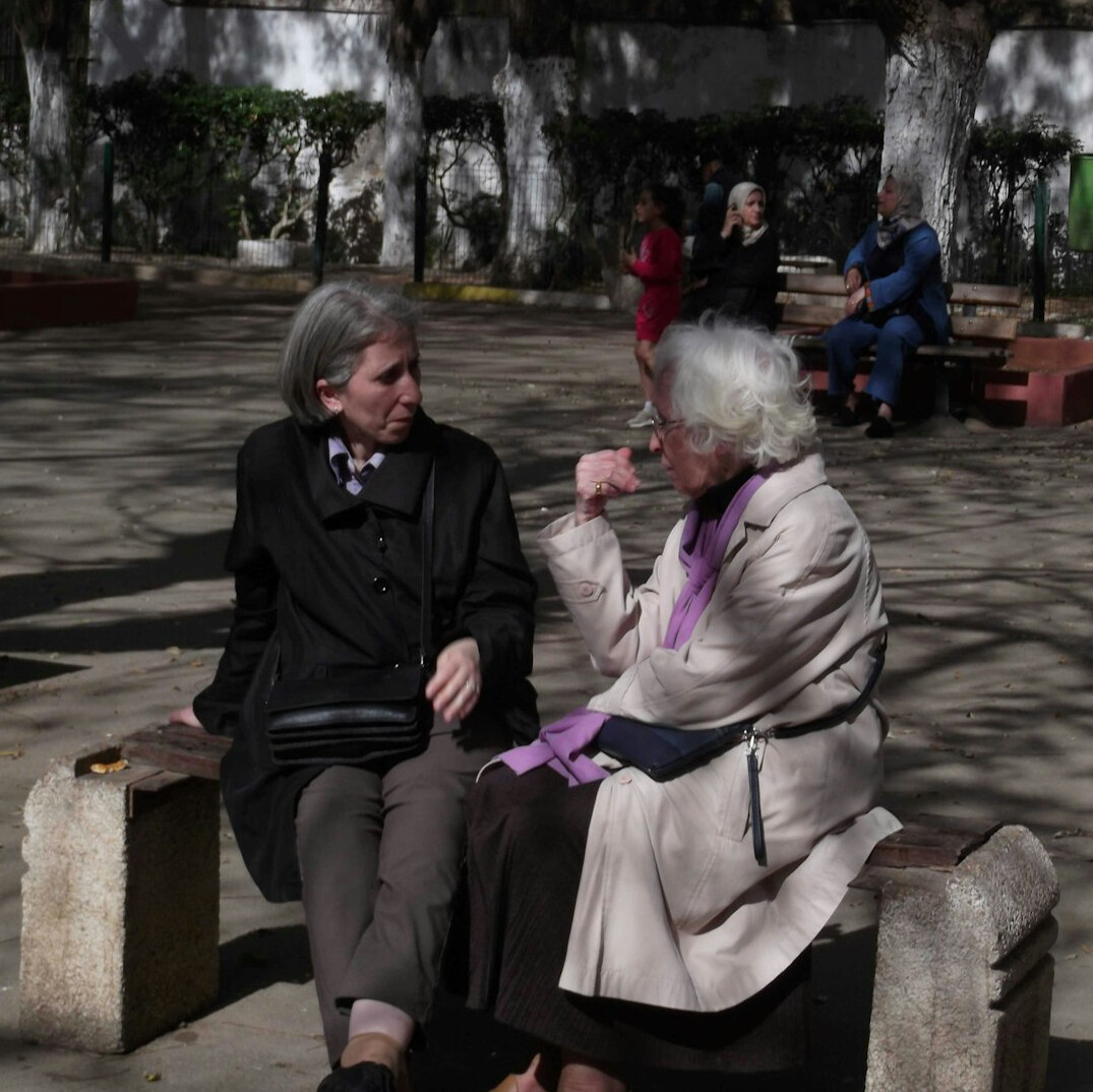 elderly people talking on bench